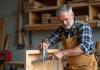 Charpentier homme vérifiant un cadre en bois dans son atelier
