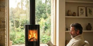 Les avantages indéniables des poêles à bois suspendus Homme d'âge moyen dans un salon cosy lisant un livre